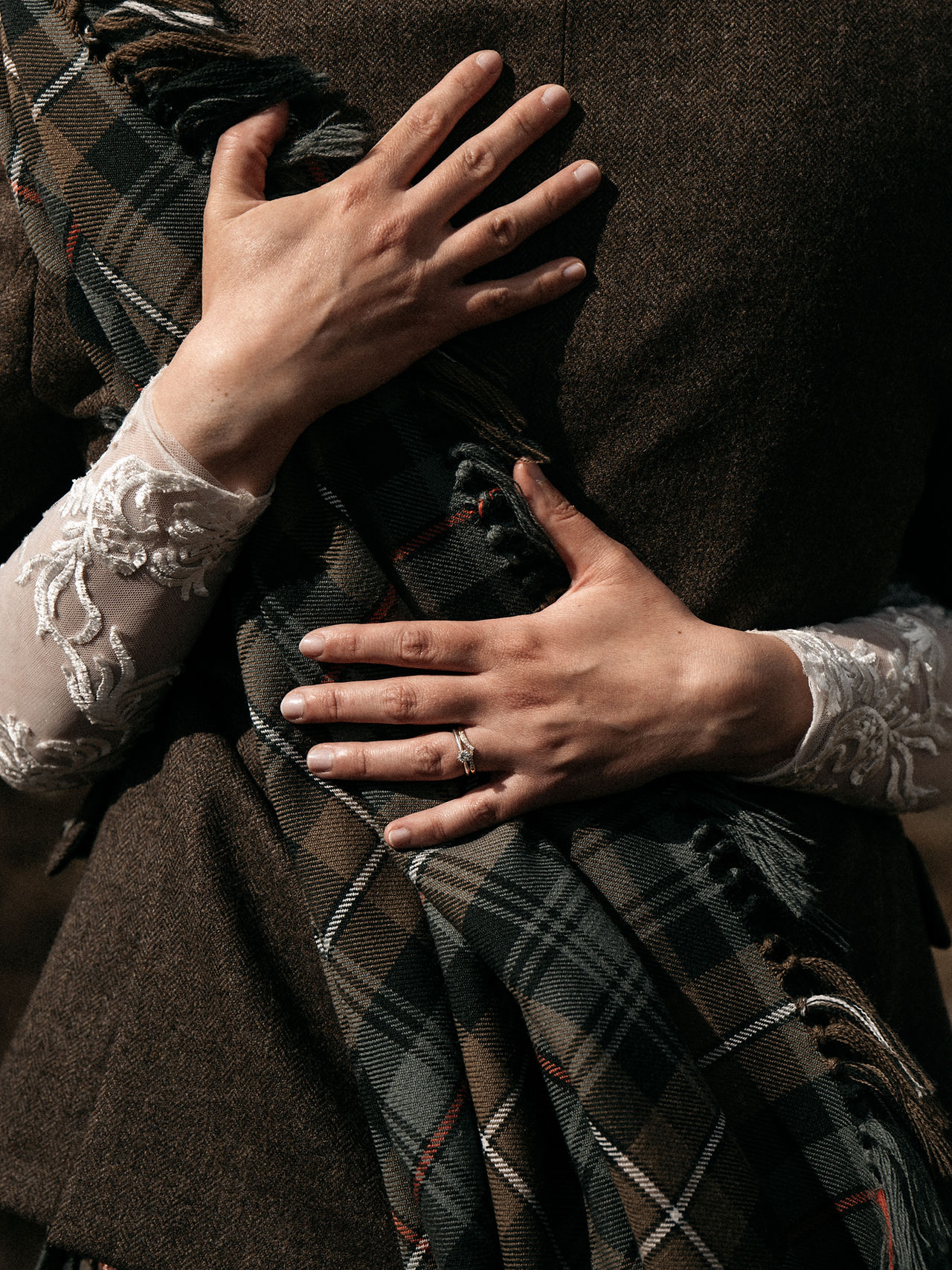 Close-up of the bride's hands resting on the groom's back