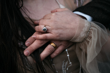 Romantic portrait of couple with groom kissing bride’s head on windswept cliffs at Duntulm Castle, Skye