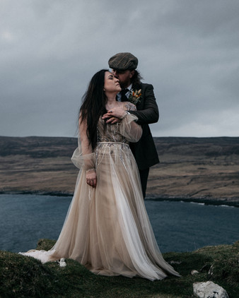 Bride leaning into groom’s chest during romantic portrait at Duntulm Castle, Isle of Skye