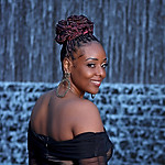Black Woman in form fitting dress in front of a waterfall
