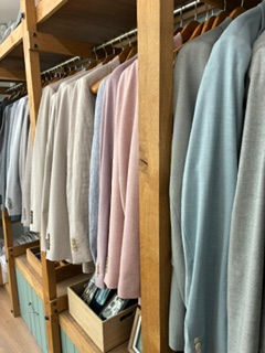 Row of sale suits hanging on a wooden rack in a clothing store, softly lit