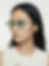 Model wearing green-tinted sunglasses in a clean fashion portrait.