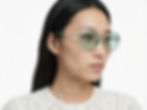 Close-up side view of green-tinted sunglasses worn by a model.