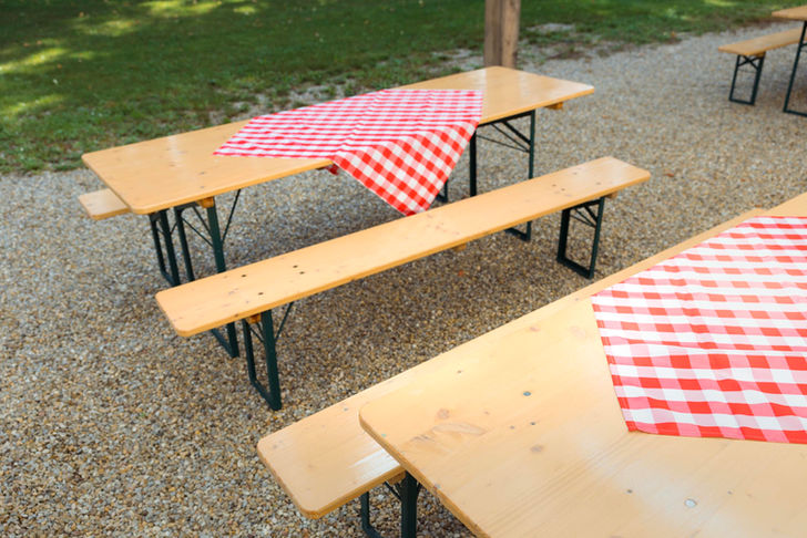 Biertischgarnituren sind mit Rot-Weiß-Karierten Tischtüchern dekoriert.