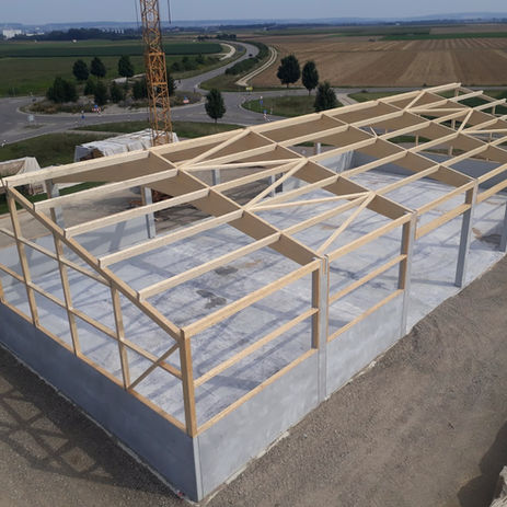Rohbau eines Gebäudes mit Betonfundament und Holz-Dachkonstruktion