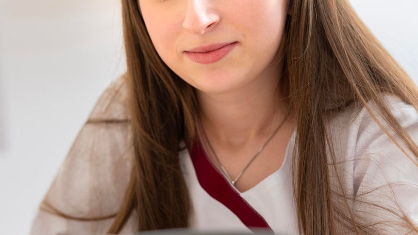 Konzentrierte junge Frau blickt auf zahnmedizinisches Gerät in Zahnarztpraxis.