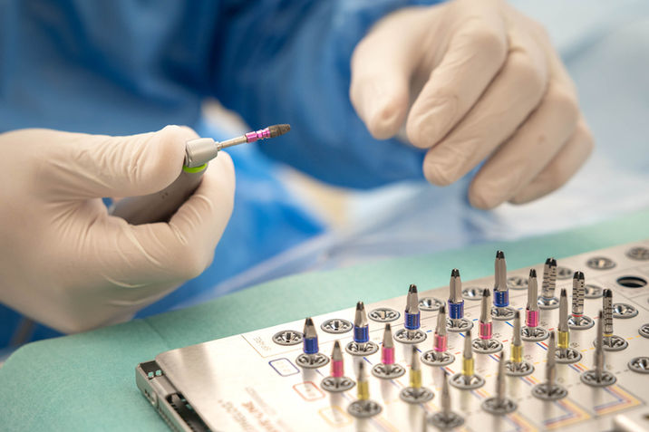 Chirurgenhände in Handschuhen halten präzises medizinisches Werkzeug neben Instrumentenablage.