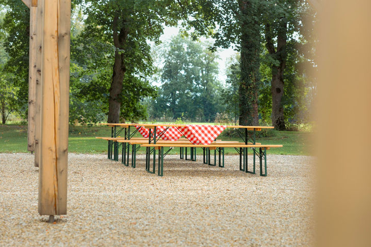 Biertisch mit rot-weiß kariertem Tischtuch im Grünen. Gut Sulz im Hintergrund.