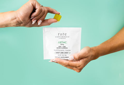 Hand hold a bag of CBD gummies. Hand hold a piece of gummy, on a green seamless background