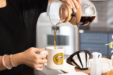 A girl pouring Hawaii coffee into a mug in a kitchen setting