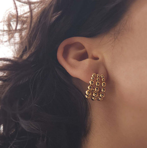Argolas douradas na orelha de uma modelo
