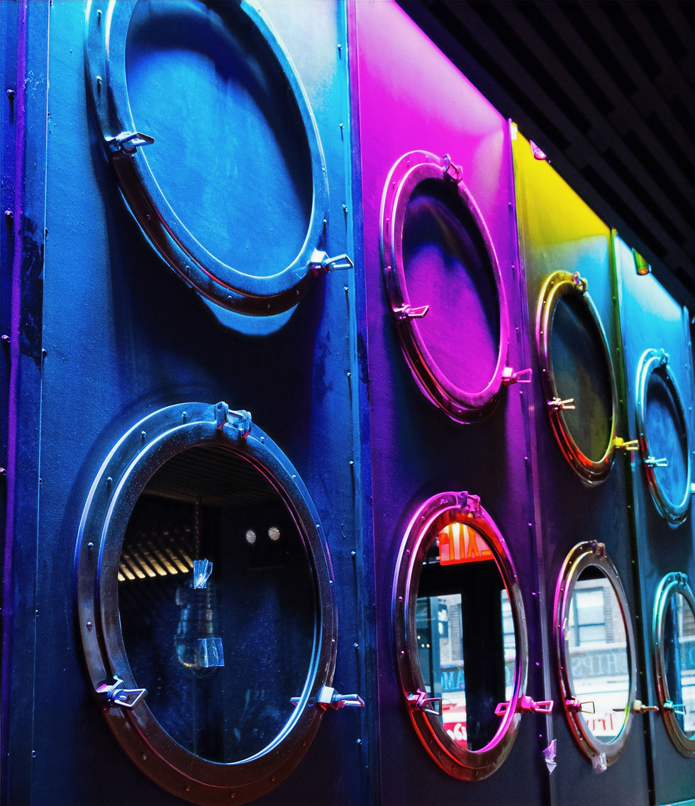 Colorful lighted portholes on a wall create a vibrant, futuristic atmosphere with pink, blue, and yellow hues reflecting urban scenery.