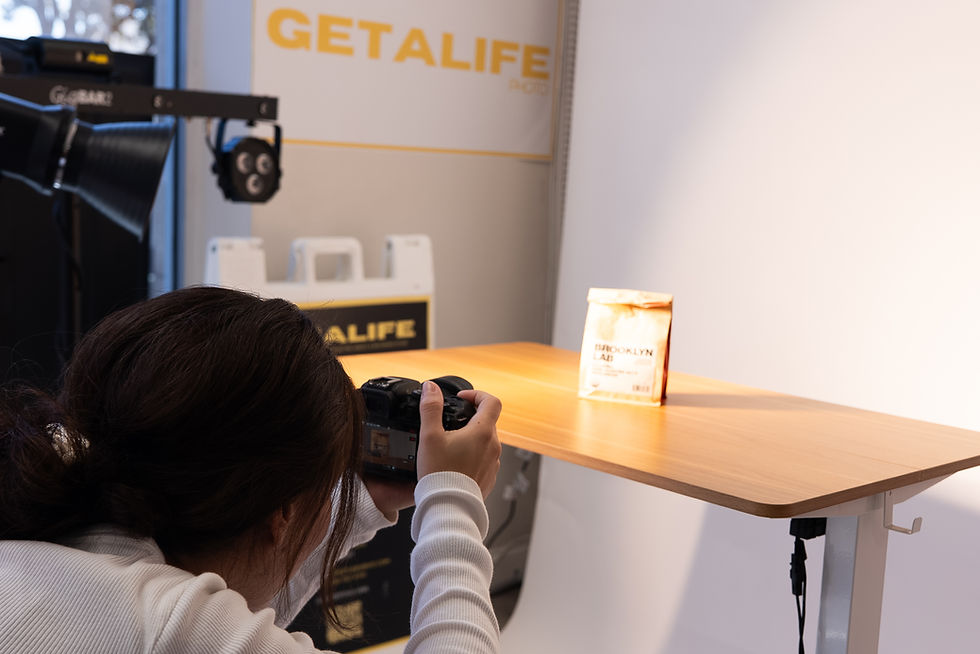 Photographer captures a bag labeled "BROOKLYN LAB" on a lit wooden table in a studio with "GETALIFE" branding in the background.