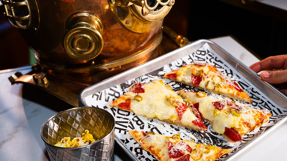Slices of pepperoni pizza on a tray with a nautical helmet nearby. A cup of popcorn is on the table. The mood is whimsical.