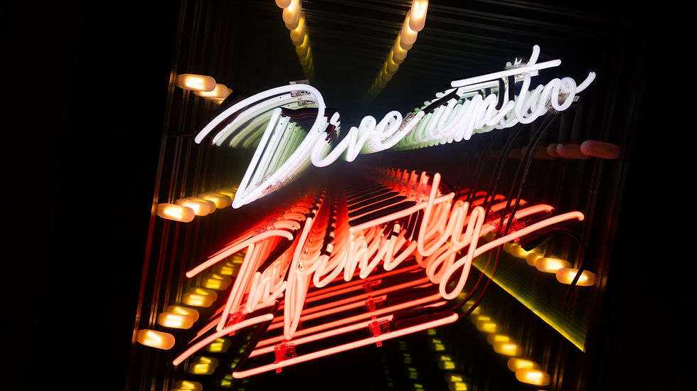 Neon sign reading "Dive into Infinity" in white and red, reflecting multiple times in a mirror-like background, creating a vibrant, infinite effect.
