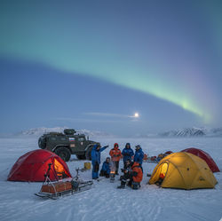 A Nenets reindeer herding family wearing traditional fur malitsa clothing, sitting together inside a