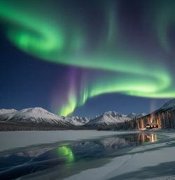 Vibrant green and purple Aurora Borealis dancing across a starry night sky over a frozen Arctic land