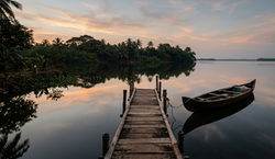Quiet Jetty at Kakkathuruth – Calm Backwater Reflections(Wooden jetty with canoe on calm backwaters 