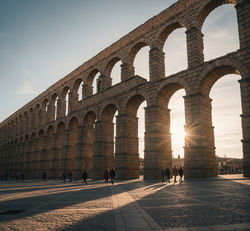 Aqueduct of Segovia ( Roman aqueduct of Segovia with people walking beneath the ancient arches )