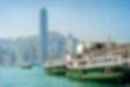 Hong Kong Bay with green and white boats with skyscapers and blue sky