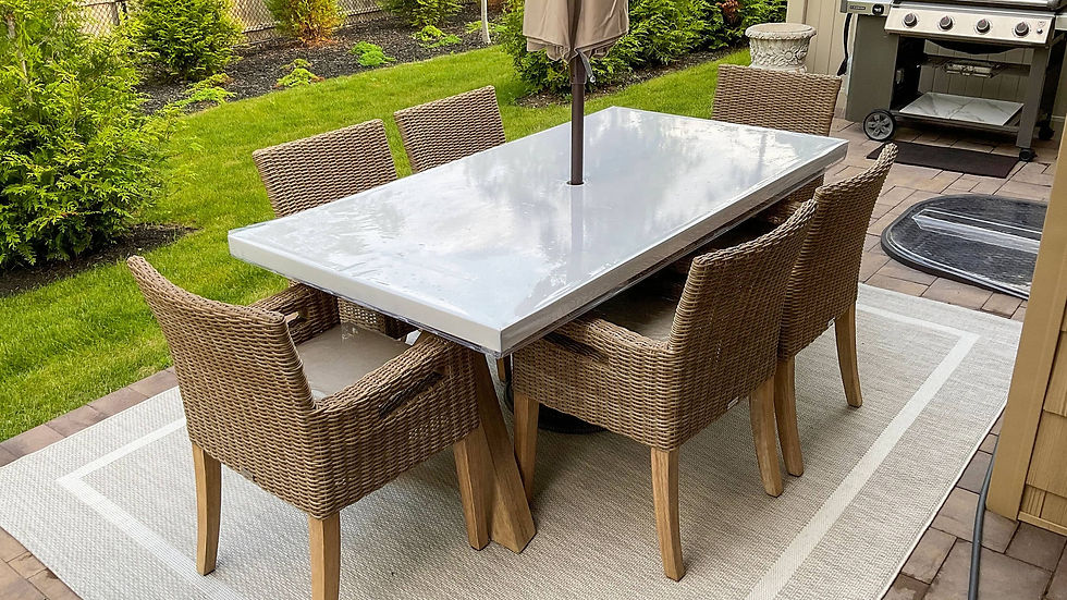 UltraClear table cover on an outdoor patio dining table with wicker chairs and a stone decor theme.
