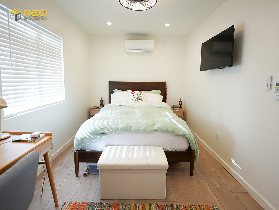 Bedroom inside a Northridge garage conversion ADU with bed, window, and wall-mounted TV.