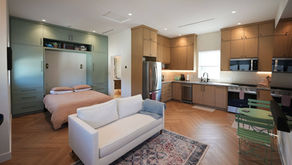 Studio ADU layout with a bed beside the kitchen and a sofa between living and sleeping areas.