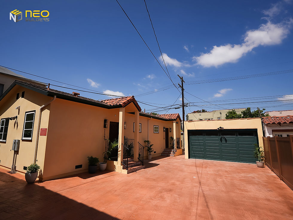 Shared courtyard between two detached ADUs and a restored historic garage in a Los Angeles HPOZ, featuring Spanish-inspired architecture and period-appropriate exterior finishes.