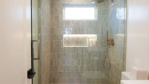 ADU shower with a recessed niche and window beside the toilet and vanity.