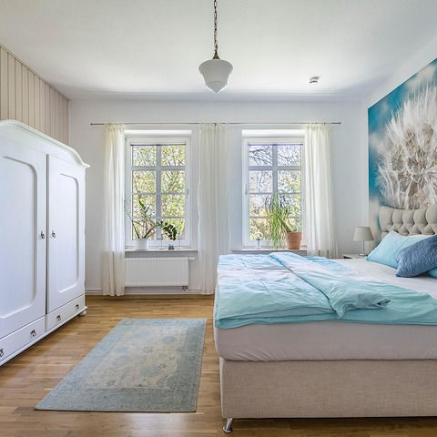 Hell eingerichtetes Schlafzimmer mit Doppelbett und Kleiderschrank