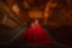 Quinceañera in a dramatic red dress posing on the grand staircase at The Brown Palace Hotel in Denver, Colorado
