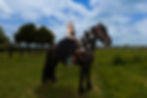 Quinceañera riding a black horse during a ranch photoshoot in Denver Colorado wearing a black quinceañera dress.