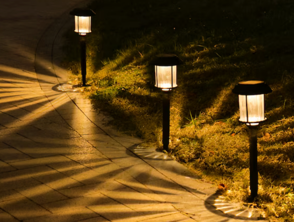 Wide angle view of glowing solar path lights illuminating a garden pathway at dusk
