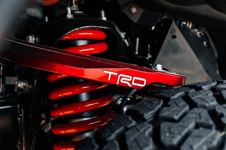 Close-up of a red TRD suspension component beside a vehicle tyre