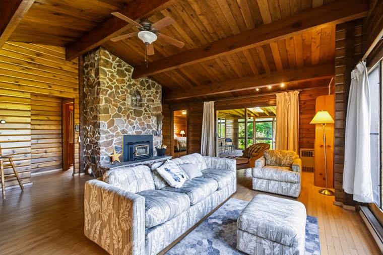 Wood-panelled living room with a stone fireplace and grey sofas