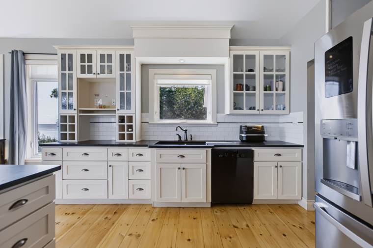 White kitchen with glass-front cabinets, a farmhouse sink and wood floors
