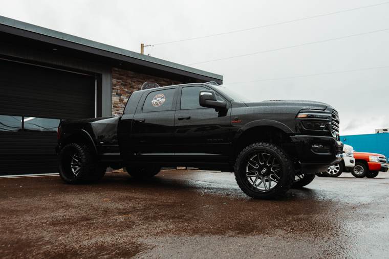 Black pickup truck parked outside a commercial building on wet pavement