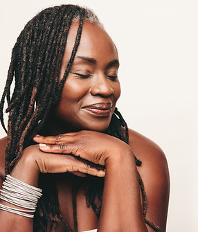 Beautiful woman with dreadlocks smiling with her eyes closed in a studio. Mature woman wea