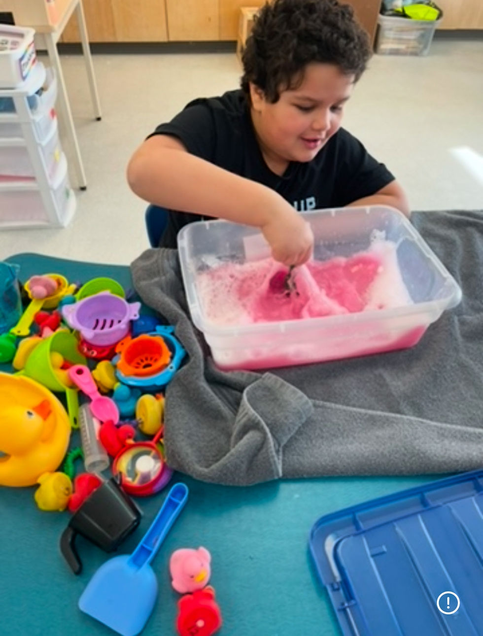 Photo of Nyus playing with sensory bin at school.