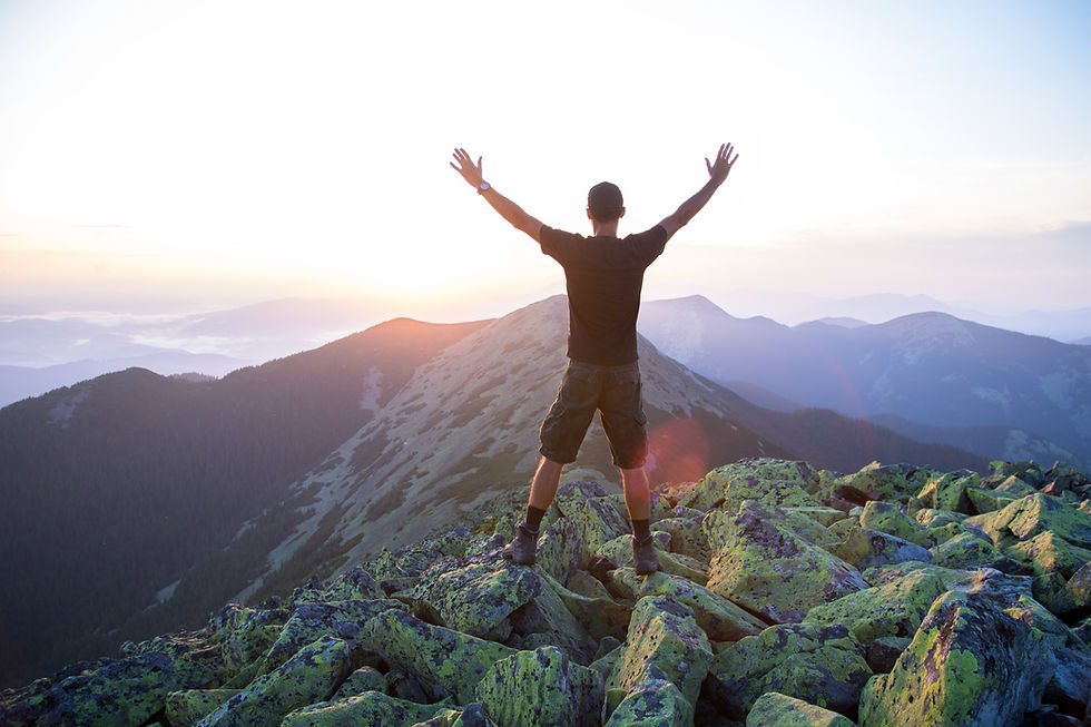 caucasian-man-hiker-is-on-the-peak-of-green-stones-mountain-watching-sunset-with-hands-in-