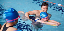 male-coach-in-water-giving-group-of-chil