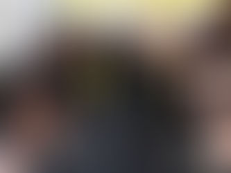 A diverse group of seven people in athletic wear standing together and smiling in a supportive strength training gym in Denver.