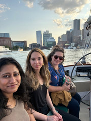 Group of people on a boat with city skyline in background at sunset.