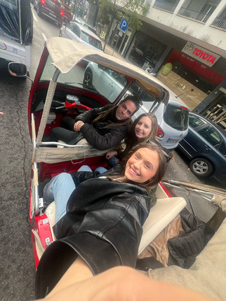 Two female students smiling while riding in a tuk-tuk with their driver.
