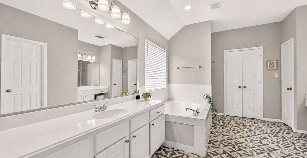 Primary bathroom double vanity with pendant lighting and white cabinetry at 835 Stevens Creek Lane, Richmond TX.