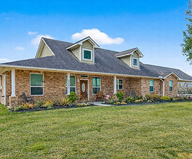 Close view of brick home exterior with covered front porch, rocking chairs, landscaped beds, and address number 35531 at Pontiac Drive, Brookshire, TX 77423