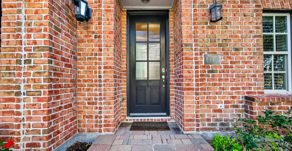 Brick front entry with black front door and coach lighting at 705 Delano Street, Houston, TX 77003
