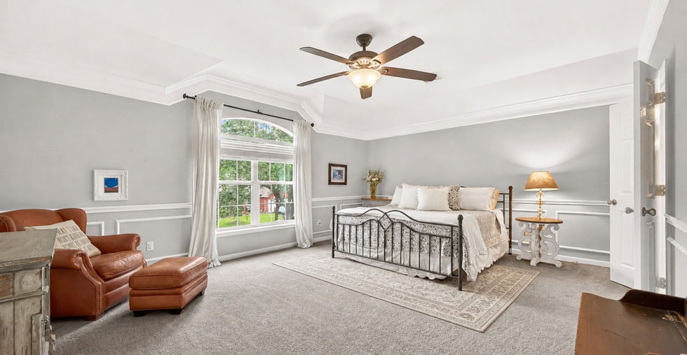 Primary bedroom with arched windows, ceiling fan, and plush carpet at 835 Stevens Creek Lane in a gated Richmond TX community.