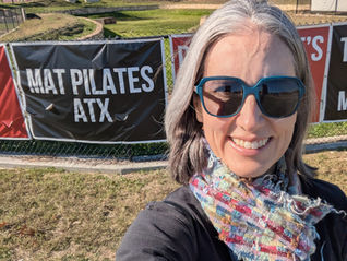 Woman smiling in front of sign with words Mat Pilates ATX