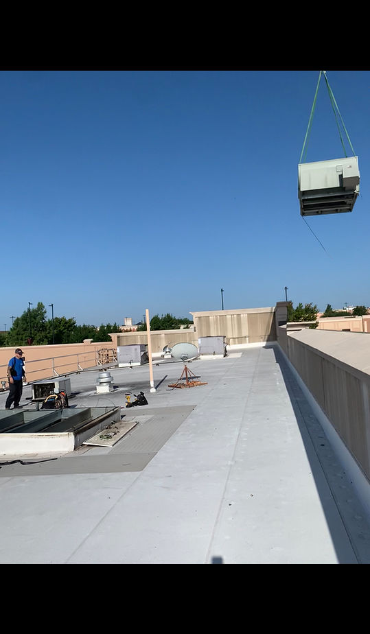 carrying HVAC commercial unit with a crane on top of commercial building